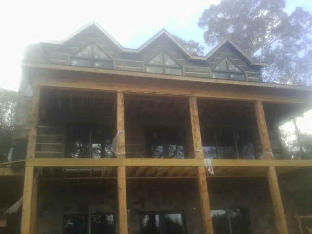 Dormers and porch framing on a large log home under construction — Roof Coating work by our crew in Canadensis