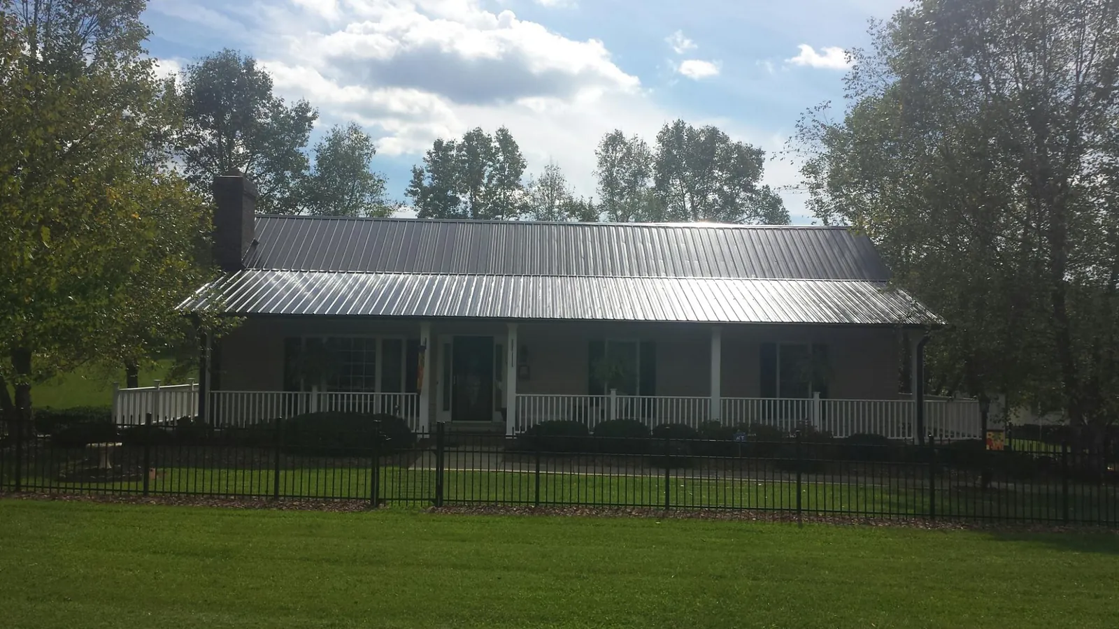 Gray metal roof on a brick ranch with a full width front porch — Gutter Guard Installation work by our crew in Canadensis