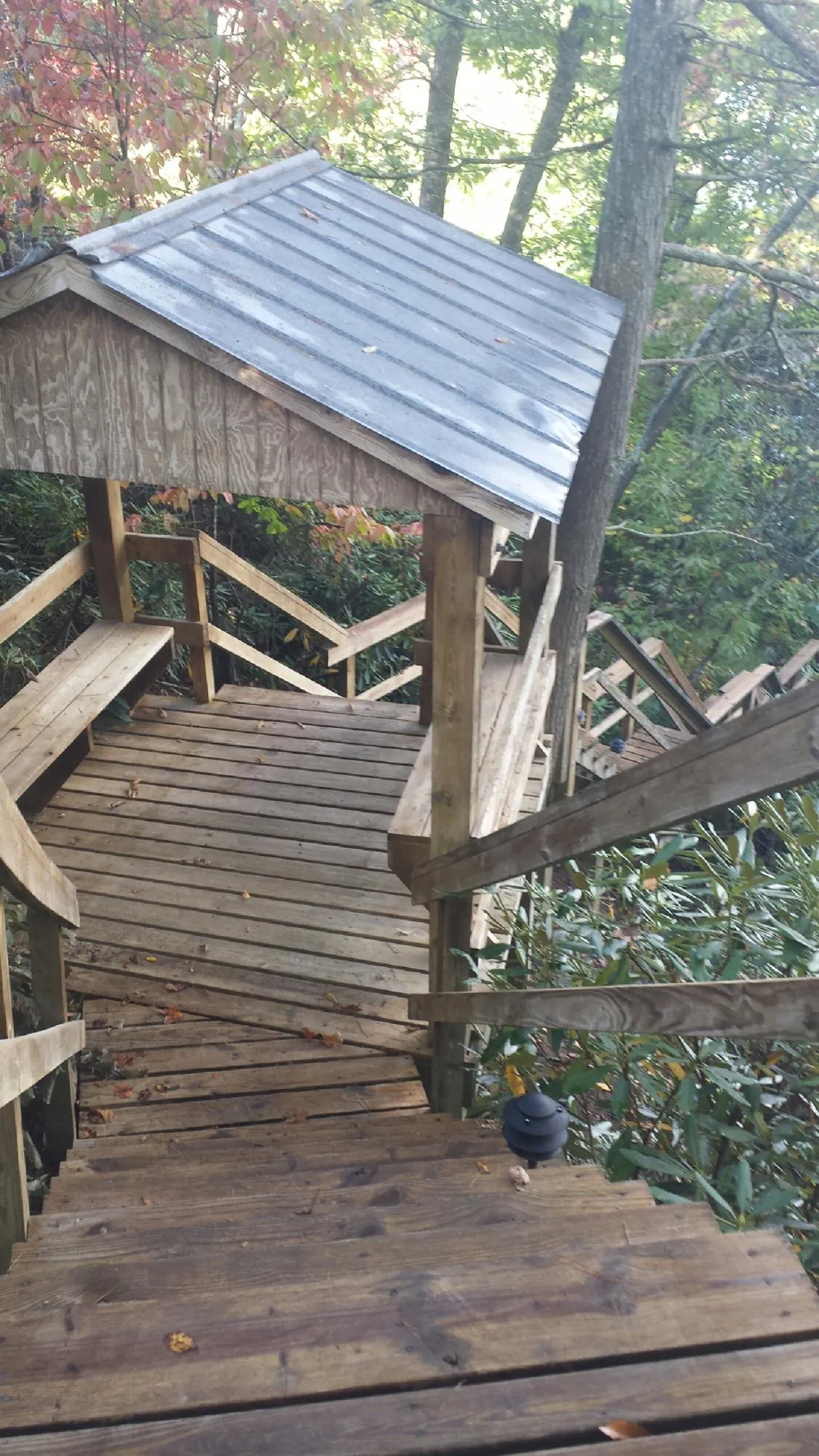 Metal roofed shelter over wooden steps on a wooded walkway — Skylight Repair & Installation work by our crew in Canadensis