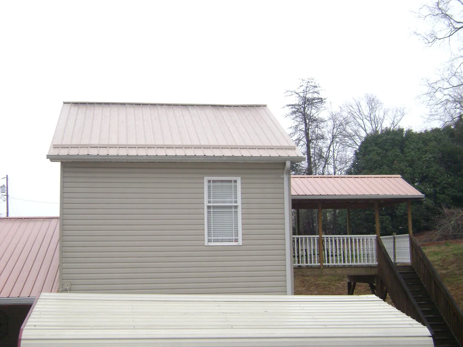 Tan metal roofs on a two story addition and attached porch, from a Roof Replacement job in Canadensis