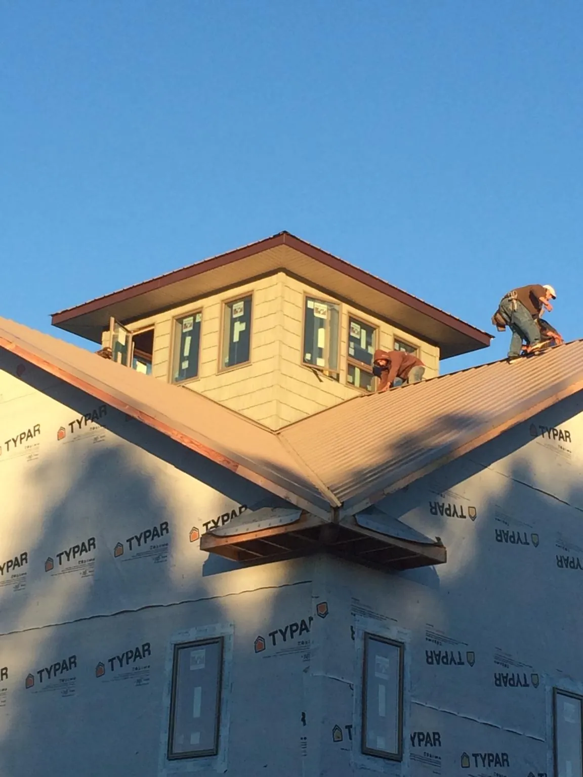 Roofers working around a rooftop cupola on a new metal roof at sunset — Roof Waterproofing in Canadensis by Roofing Brothers